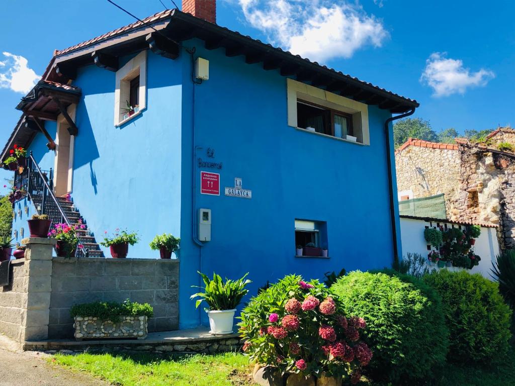 uma casa azul com flores em frente em La Galayca em El Barcenal