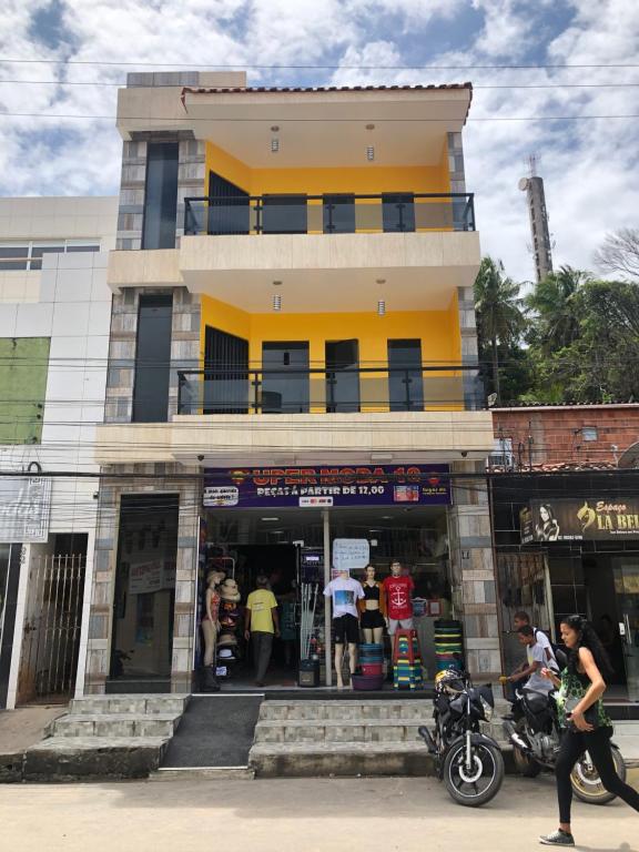 una tienda frente a un edificio amarillo con una motocicleta delante en Flats Manacá Maragogi, en Maragogi