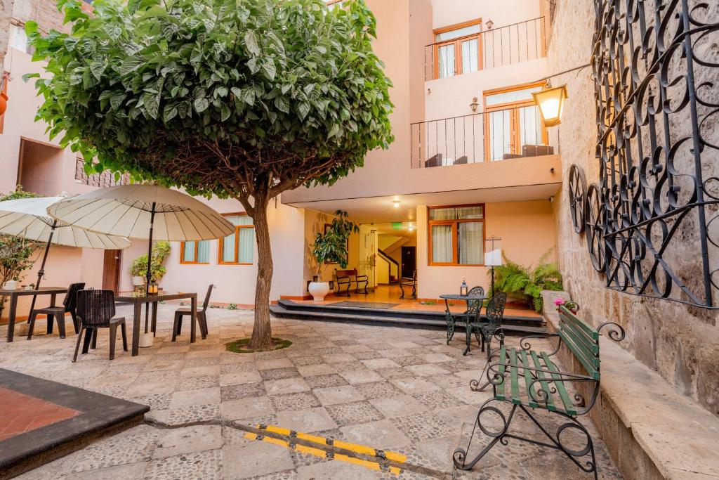 a courtyard with tables and chairs and a tree at Hotel Los Tambos Colonial in Arequipa
