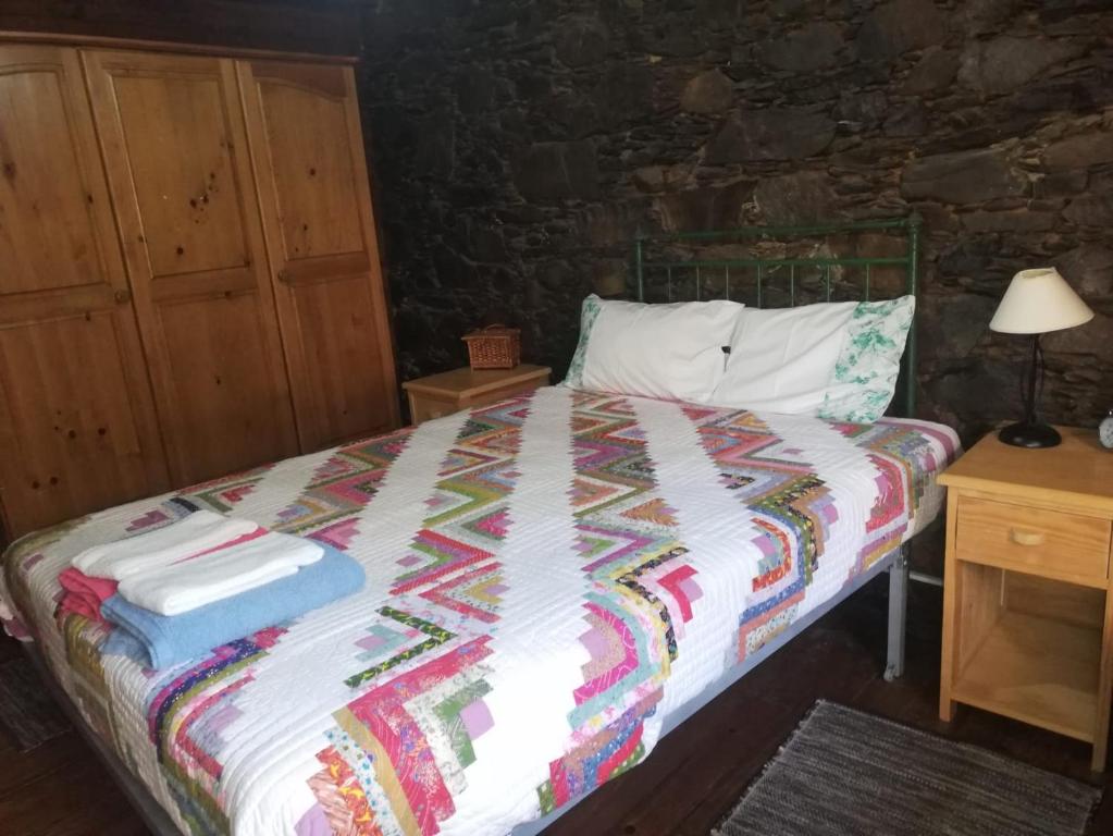 1 dormitorio con 1 cama con una manta colorida en Casa das Tias, en Lousã