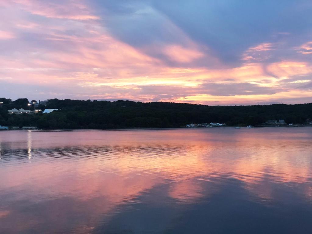 einen Sonnenuntergang über einem großen Wasserkörper in der Unterkunft Spectacular home with a amazing ocean - river view in Groton
