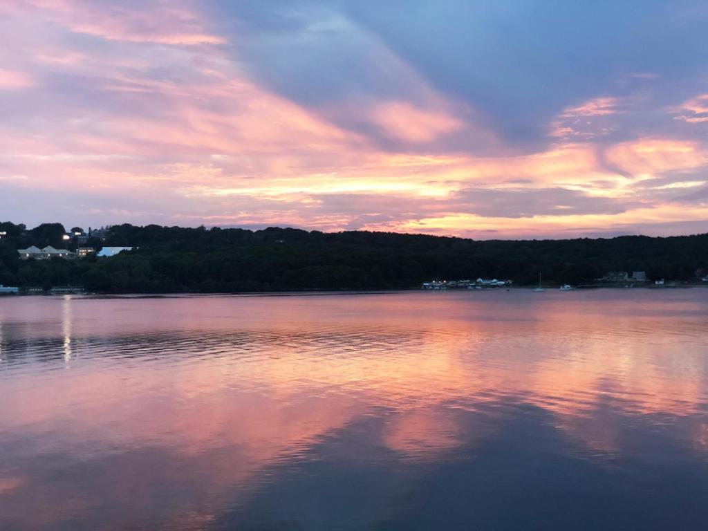 a sunset over a large body of water at Spectacular home with a amazing ocean - river view in Groton
