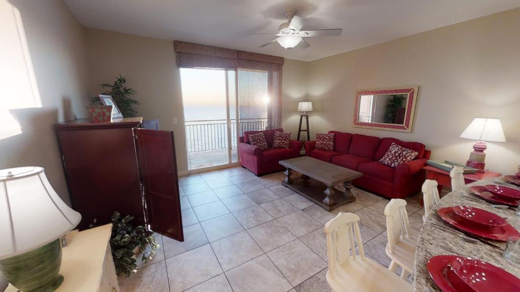 uma sala de estar com um sofá vermelho e uma mesa em Splash 1204 E em Panama City Beach