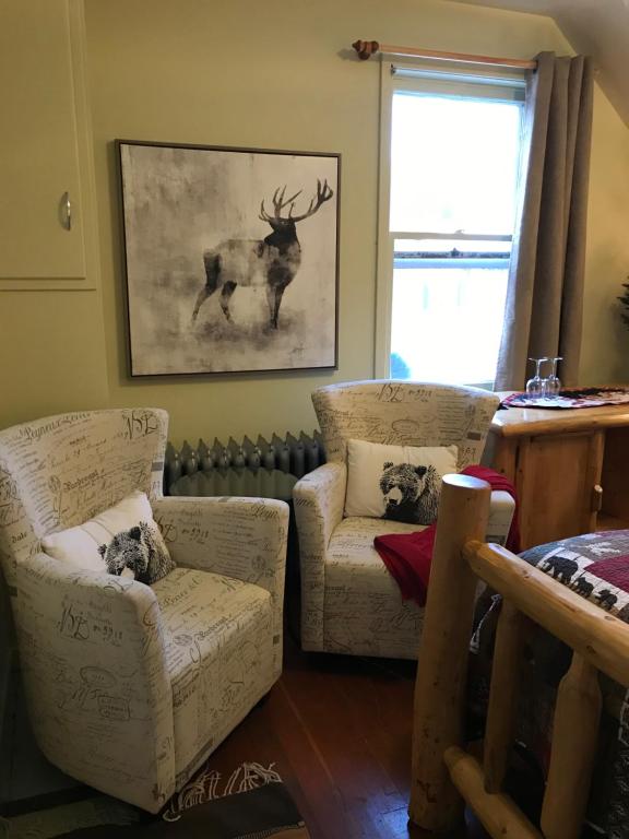 a living room with two chairs and a picture of a deer at Holiday Lodge Bed and Breakfast in Banff
