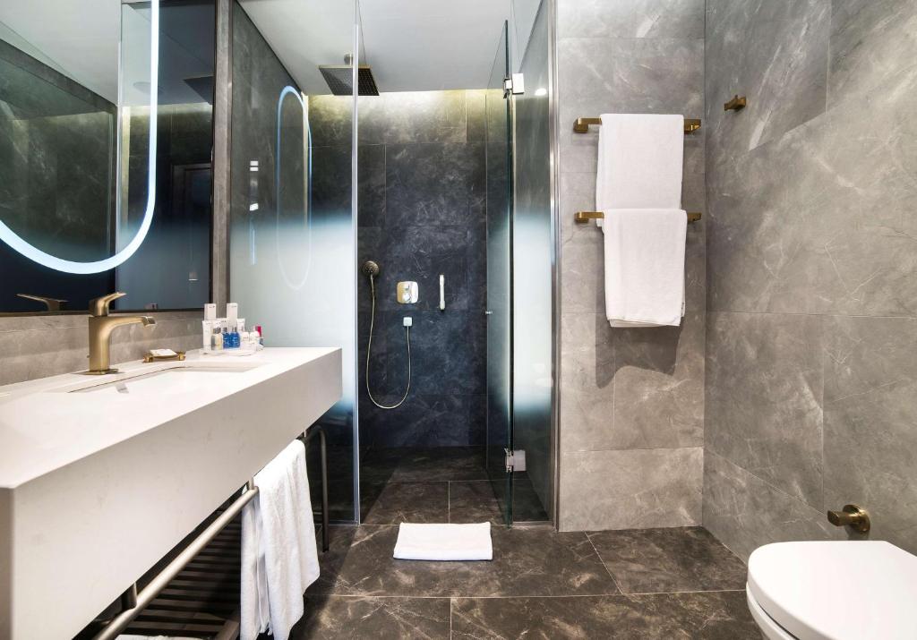 a bathroom with a shower and a sink and a toilet at Radisson Collection Hotel, Vadistanbul in Istanbul