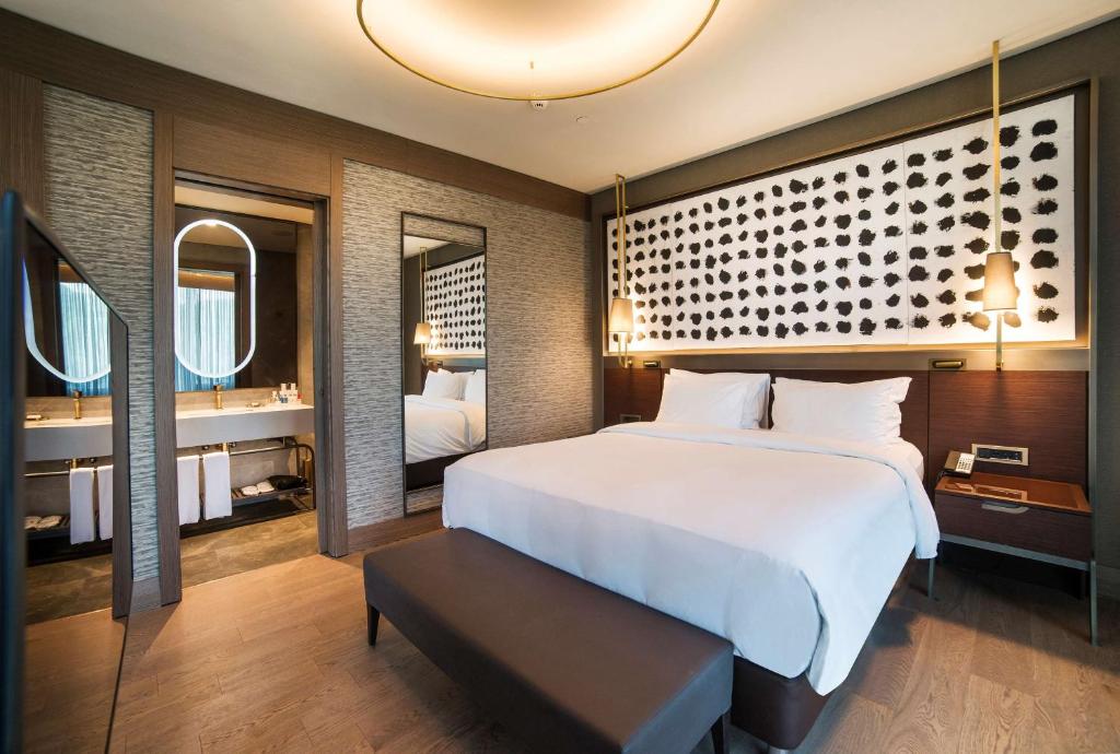 a bedroom with a large white bed and two mirrors at Radisson Collection Hotel, Vadistanbul in Istanbul