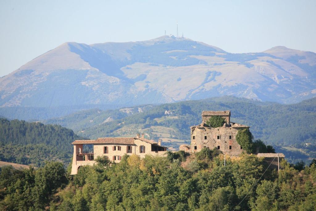 un grupo de edificios en una colina con montañas en el fondo en Agriturismo Monte Valentino, en Pietralunga