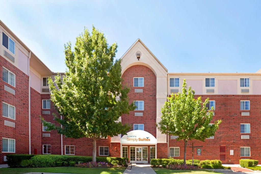 a large brick building with trees in front of it at Sonesta Simply Suites Arlington in Arlington