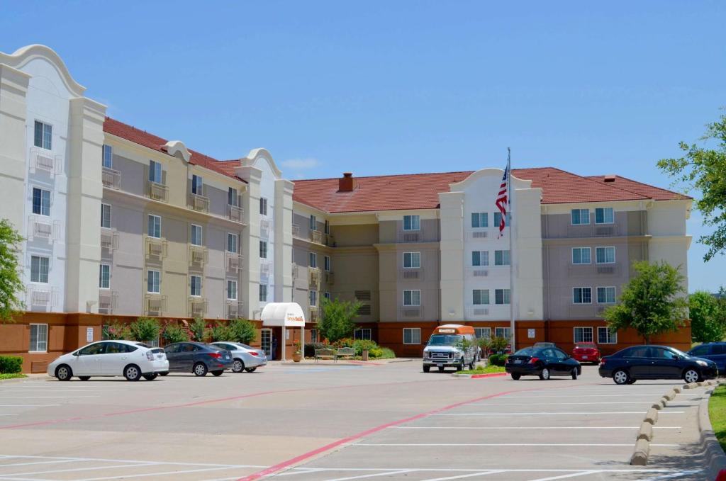 a large building with cars parked in a parking lot at Sonesta Simply Suites Dallas Las Colinas in Irving