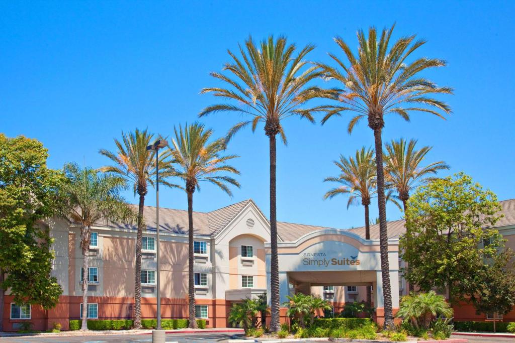 a row of palm trees in front of a building at Sonesta Simply Suites Orange County Airport in Santa Ana
