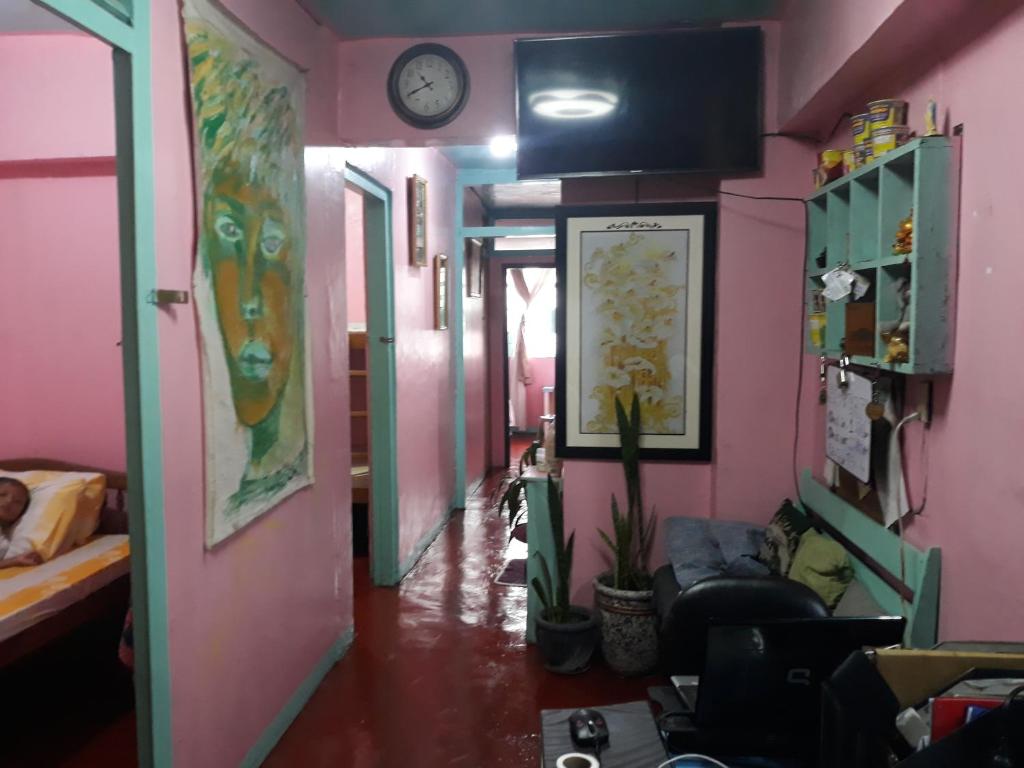 um corredor com um quarto com paredes cor-de-rosa e um relógio em CVBNB BAGUIO GUESTHOUSE em Baguio