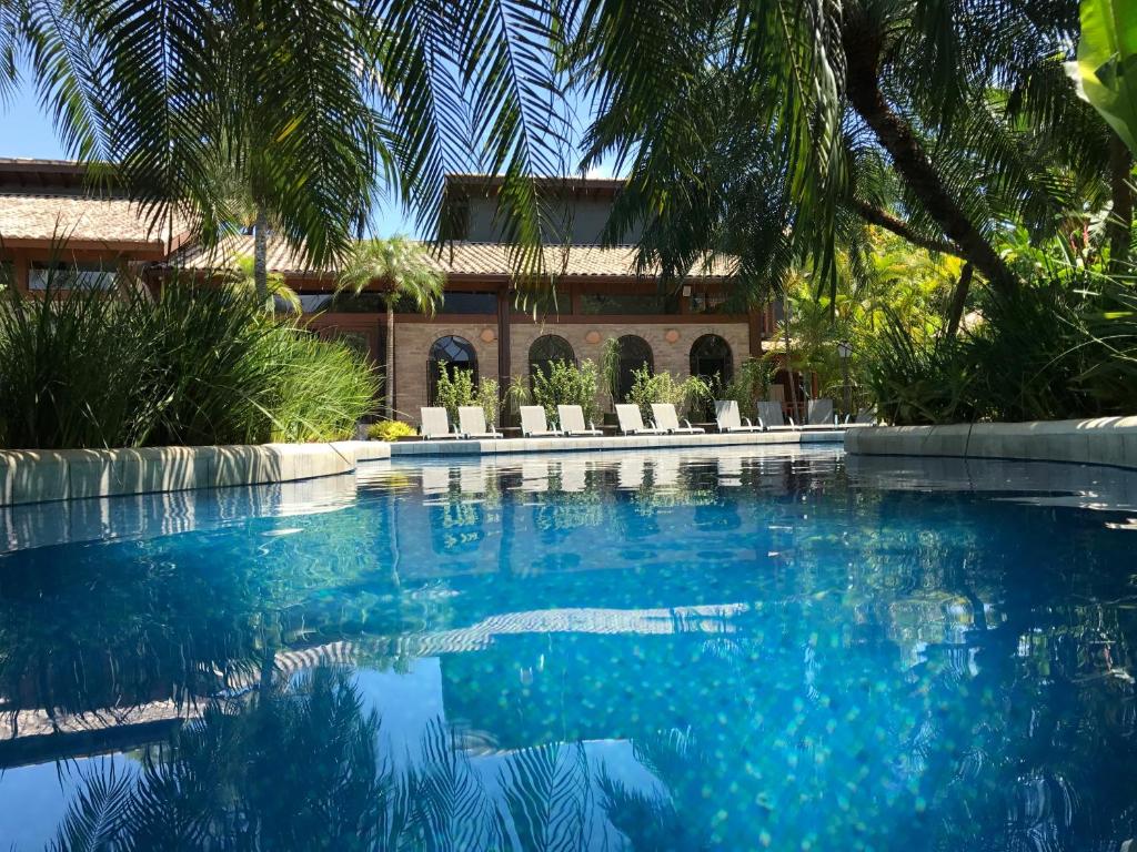 a swimming pool in front of a house with palm trees at Villa Bebek Hotel in Camburi