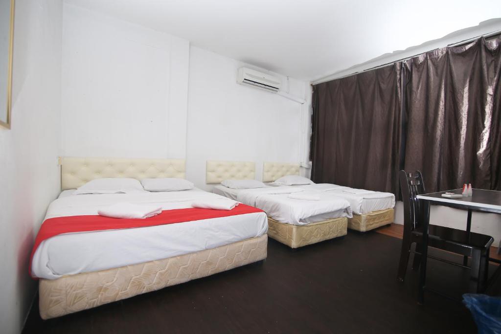 a bedroom with two beds and a desk and a table and a table at L&C Premium Stay in Kuching