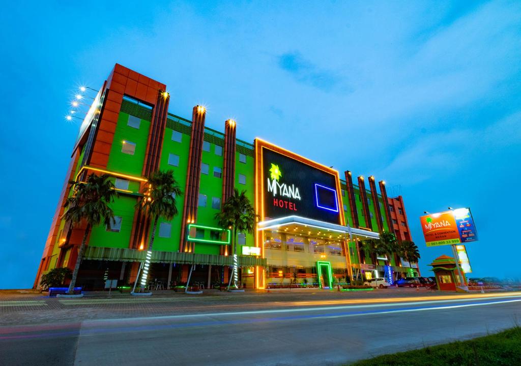um grande edifício com um letreiro de néon em frente a uma rua em Miyana Hotel em Medan