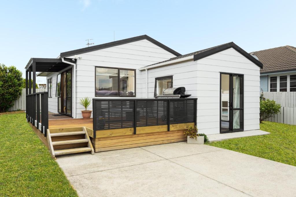a small white house with a deck at The Mount Beach Pad - Mt Maunganui Holiday Home in Matapihi