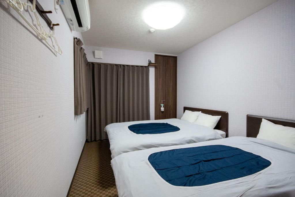a hotel room with two beds with blue sheets at Rokuhara Inn in Kyoto