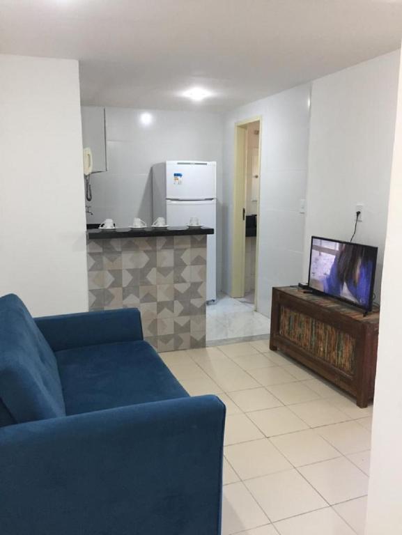Una sala de estar con un sofá azul y un televisor. en Hospedagem da Rose - Cabo Frio, en Cabo Frío