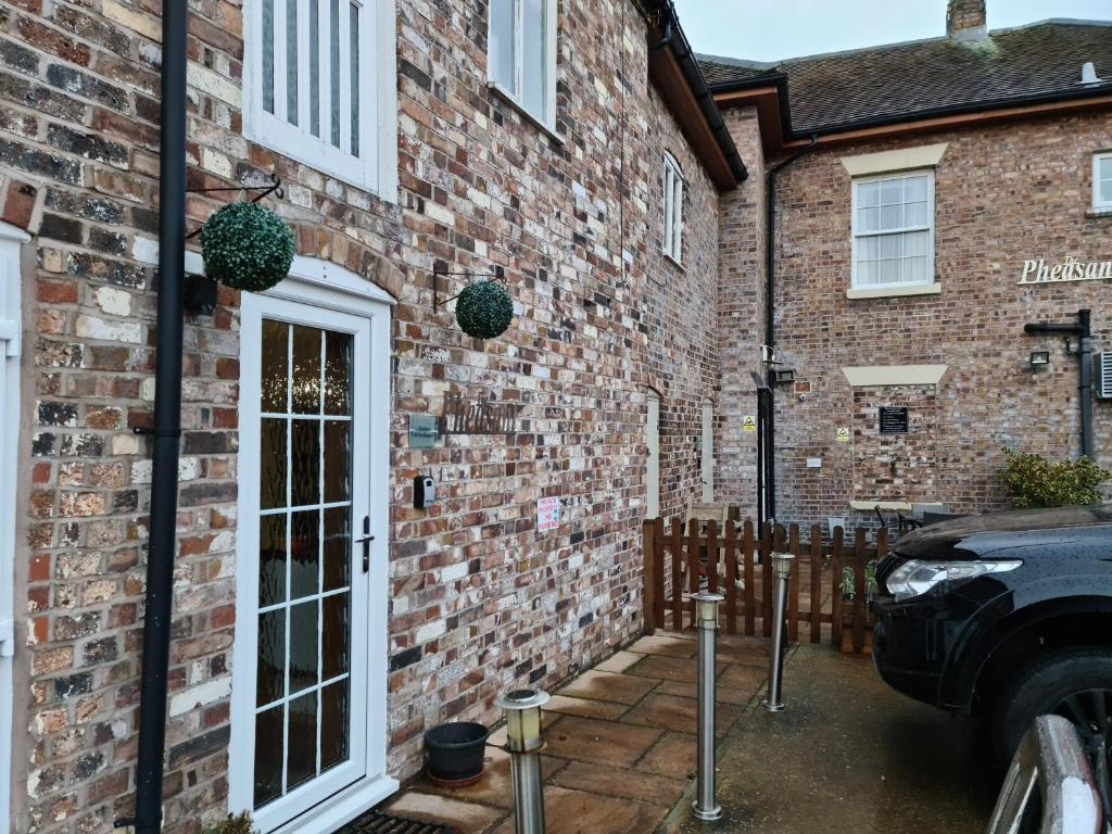 un edificio de ladrillo con una puerta y un coche aparcado fuera en The Mews @ The Pheasant, en Ironbridge