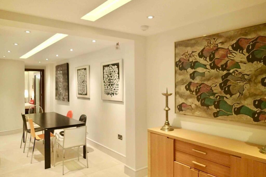 a dining room with a table and a painting on the wall at Stylish large cool 3 bed 3 bath Marylebone +AC in London