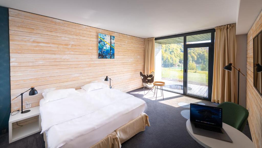 a bedroom with a large bed and a desk with a laptop at Pensiunea Atra Doftana in Teşila