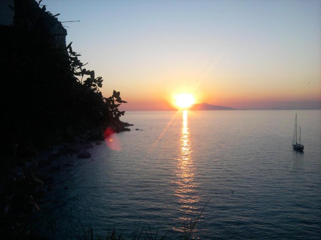einen Sonnenuntergang über einem Wasserkörper mit einem Boot in der Unterkunft B&B Palazzo a Mare in Capri