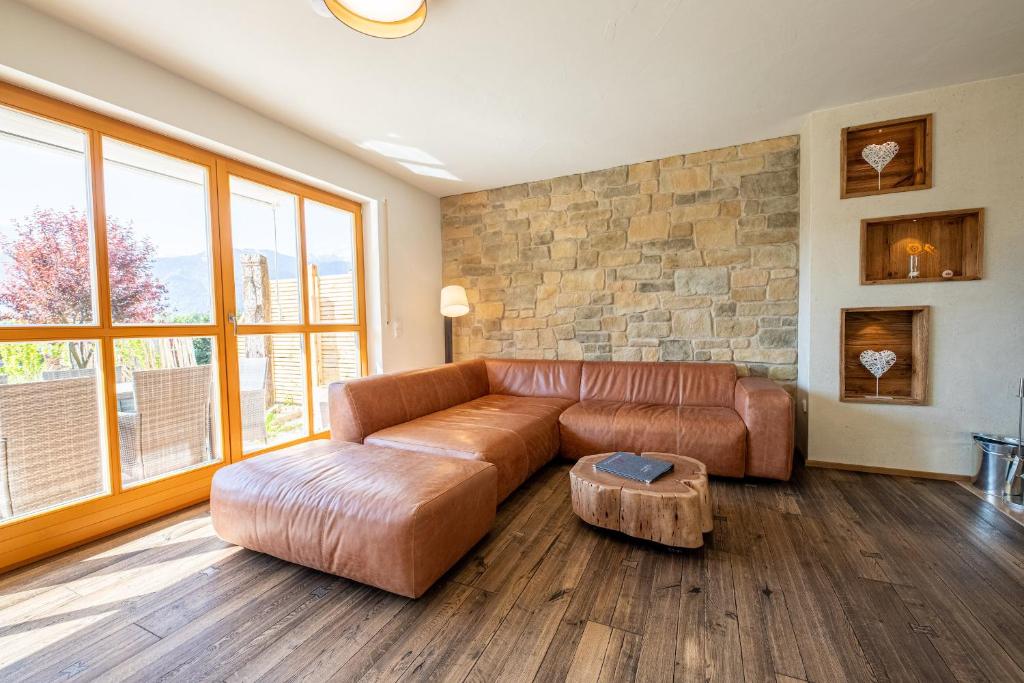 a living room with a leather couch and a stone wall at Ferienhaus „Adlerhorst“ eignet sich ideal für die ganze Familie in Garmisch-Partenkirchen