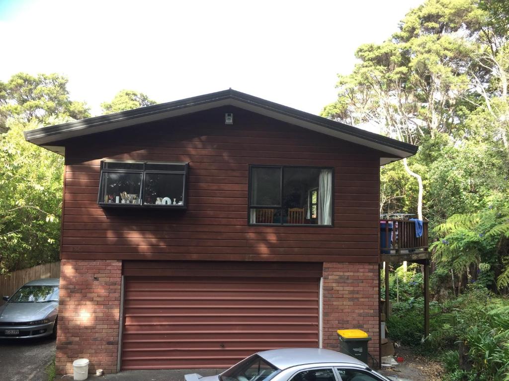 a house with a garage door and two windows at Bush , birds and relaxing moments in Auckland