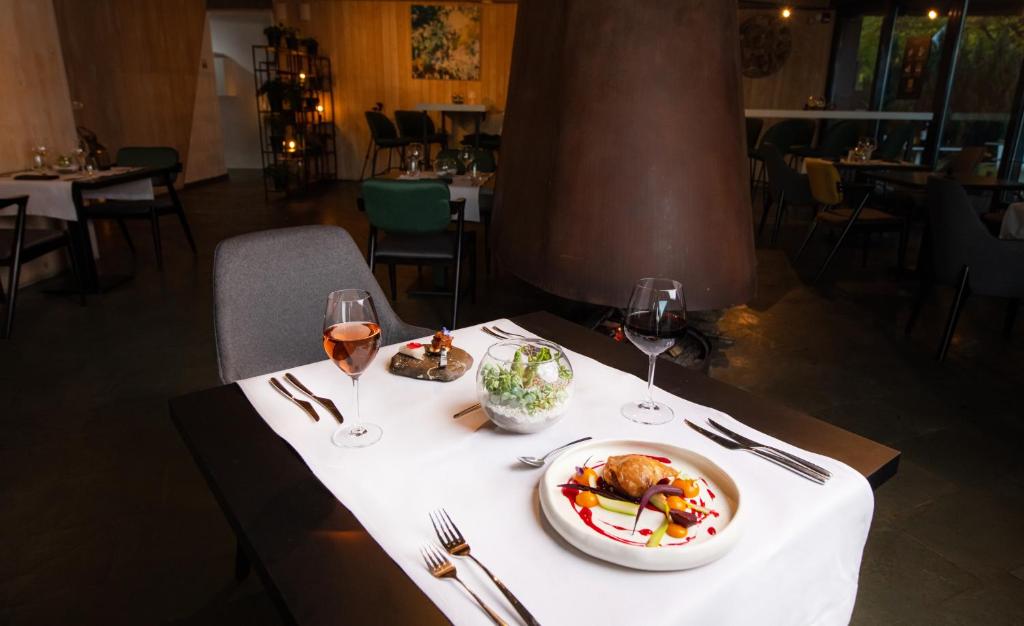 a table with a plate of food and two glasses of wine at Pensiunea Atra Doftana in Teşila