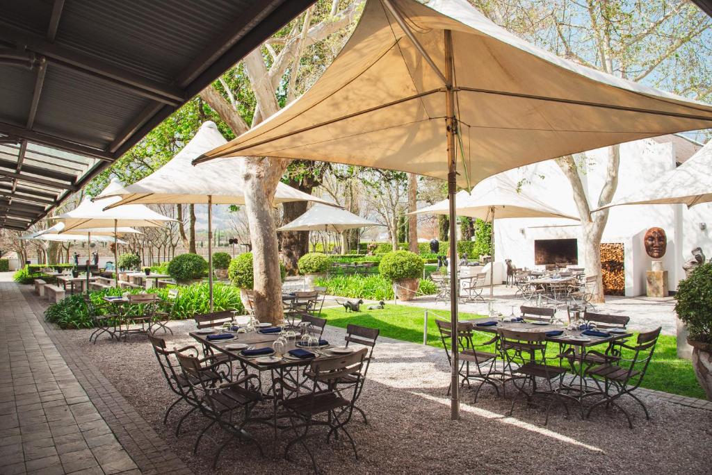 un gruppo di tavoli e sedie sotto un ombrellone di Grande Provence a Franschhoek