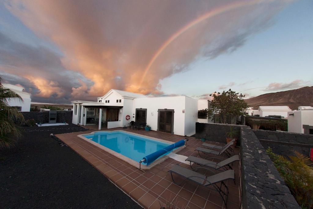 a house with a pool and a rainbow in the sky at Villa Marina Deluxe & Spa Pool in Playa Blanca