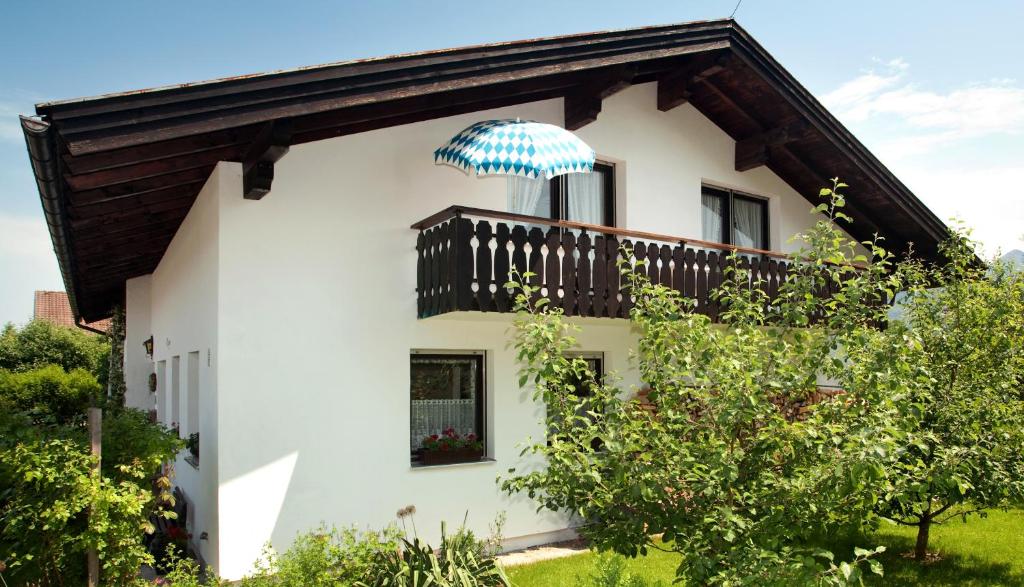 a white house with a balcony with an umbrella on it at Ferienwohnung Daiber in Bernau am Chiemsee