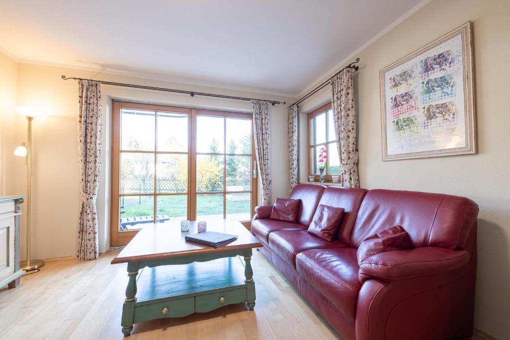 a living room with a red leather couch and a table at Alpensonne in Garmisch-Partenkirchen