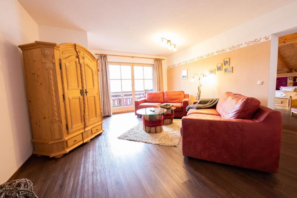 a living room with a red couch and a large cabinet at Edelrose in Grainau