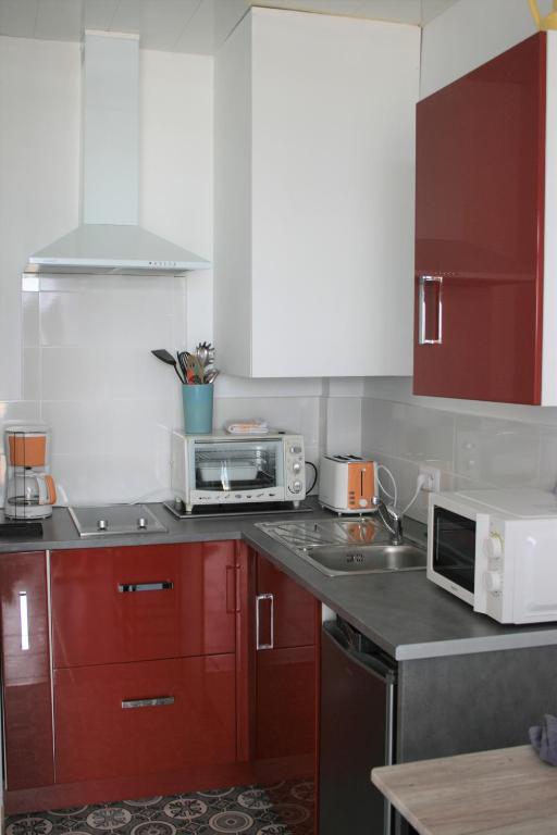 a kitchen with red cabinets and a microwave at escapade en mer in Ault