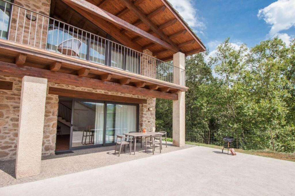 a patio of a house with a table and a grill at La Cabanya Planella in Vall de Bianya