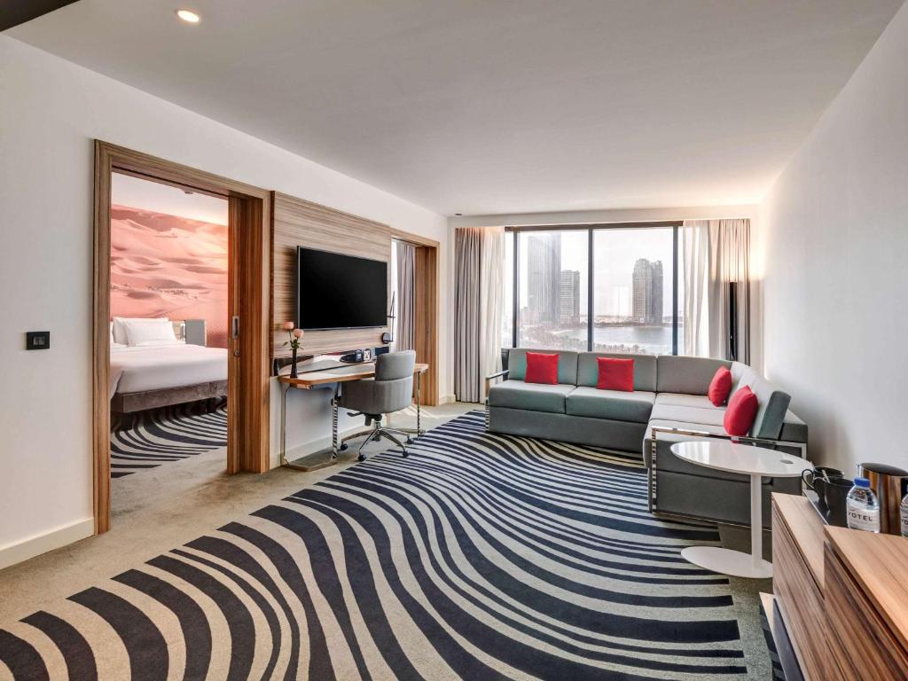 a living room with a couch and a television at Novotel Sharjah Expo Centre in Sharjah