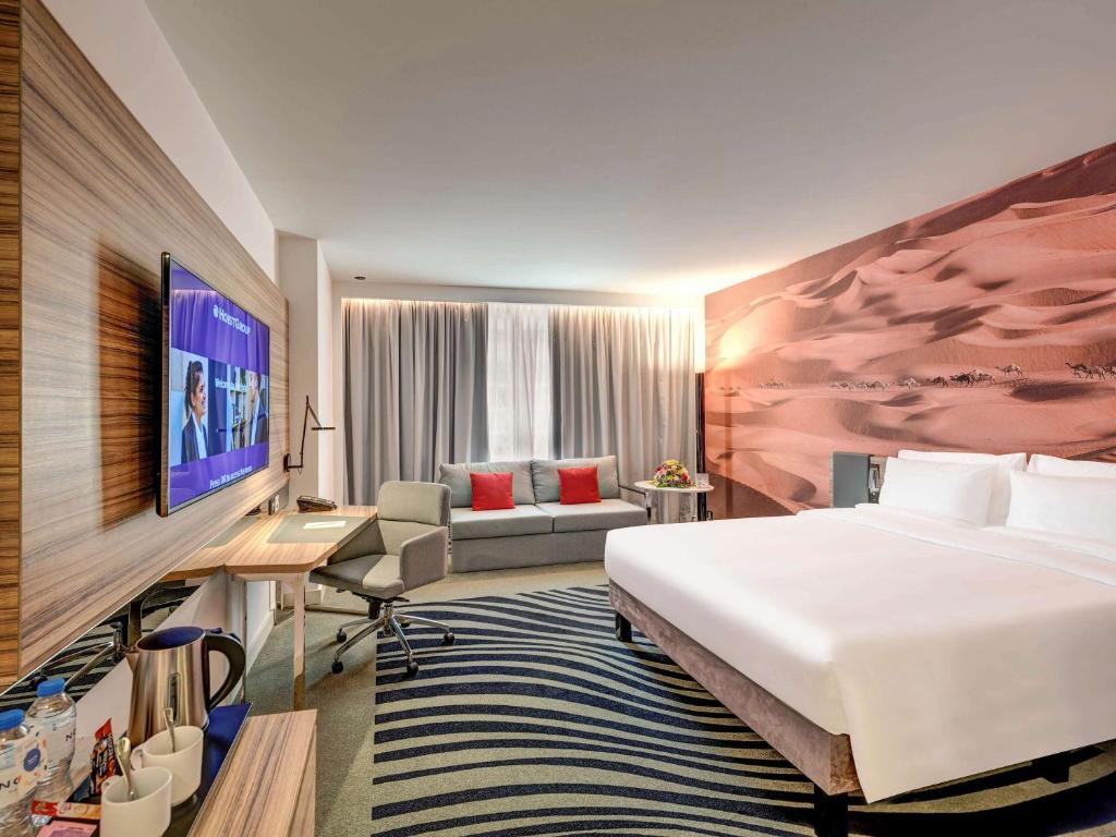 a hotel room with a bed and a desk at Novotel Sharjah Expo Centre in Sharjah