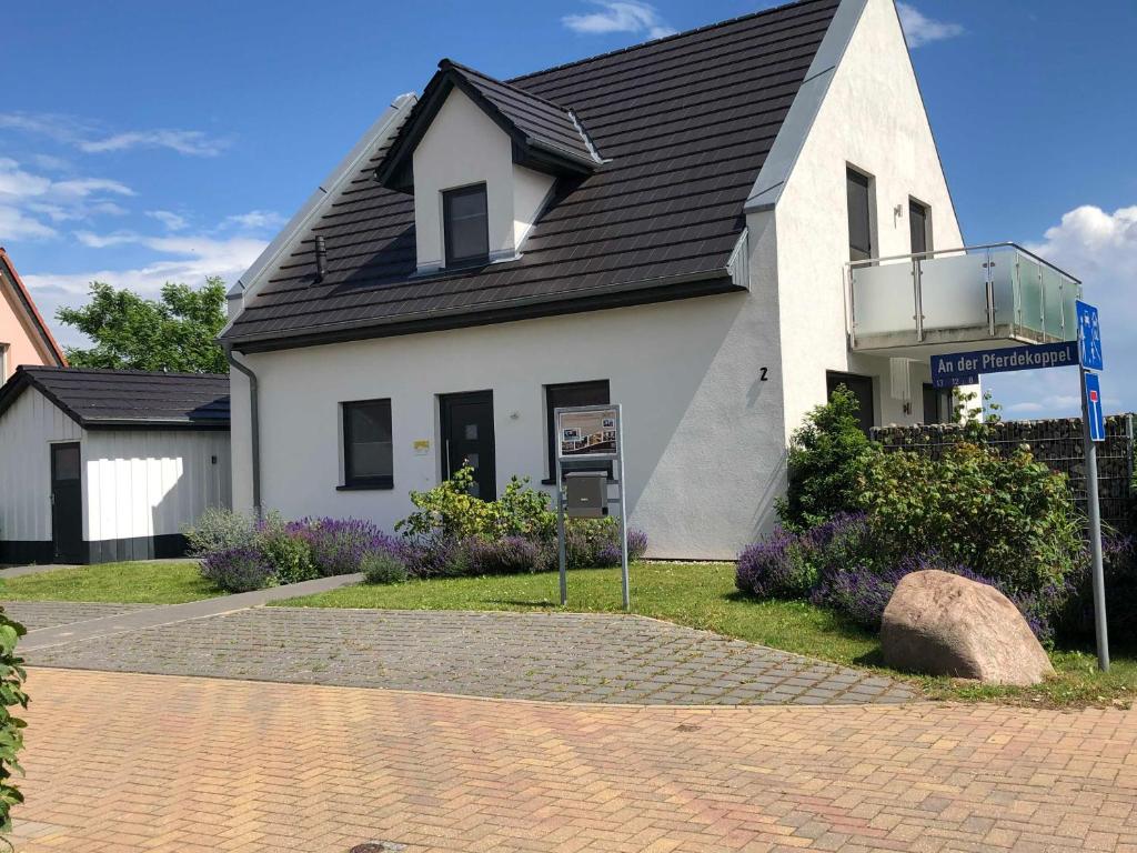 a white house with a black roof on a street at Ferienhaus Villa Major in Göhren-Lebbin