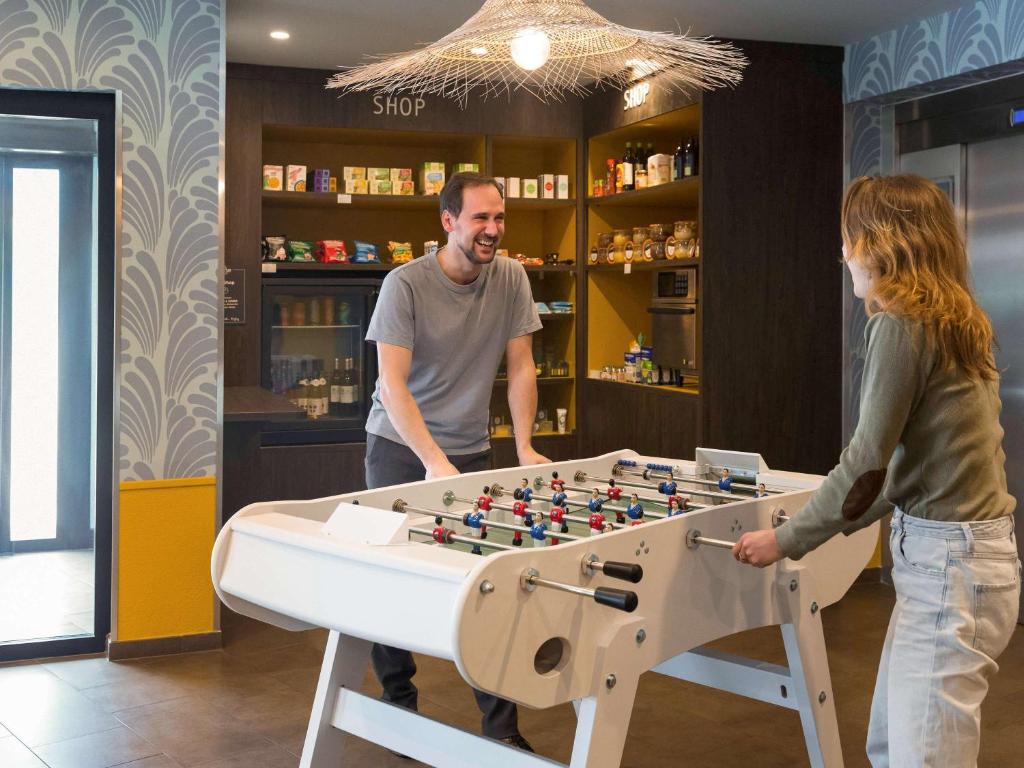 een man en een vrouw die met een tafelvoetbalspel spelen bij Aparthotel Adagio Annecy Centre in Annecy