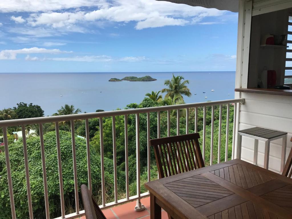 a balcony with a table and chairs and the ocean at villa Azur A in Bouillante