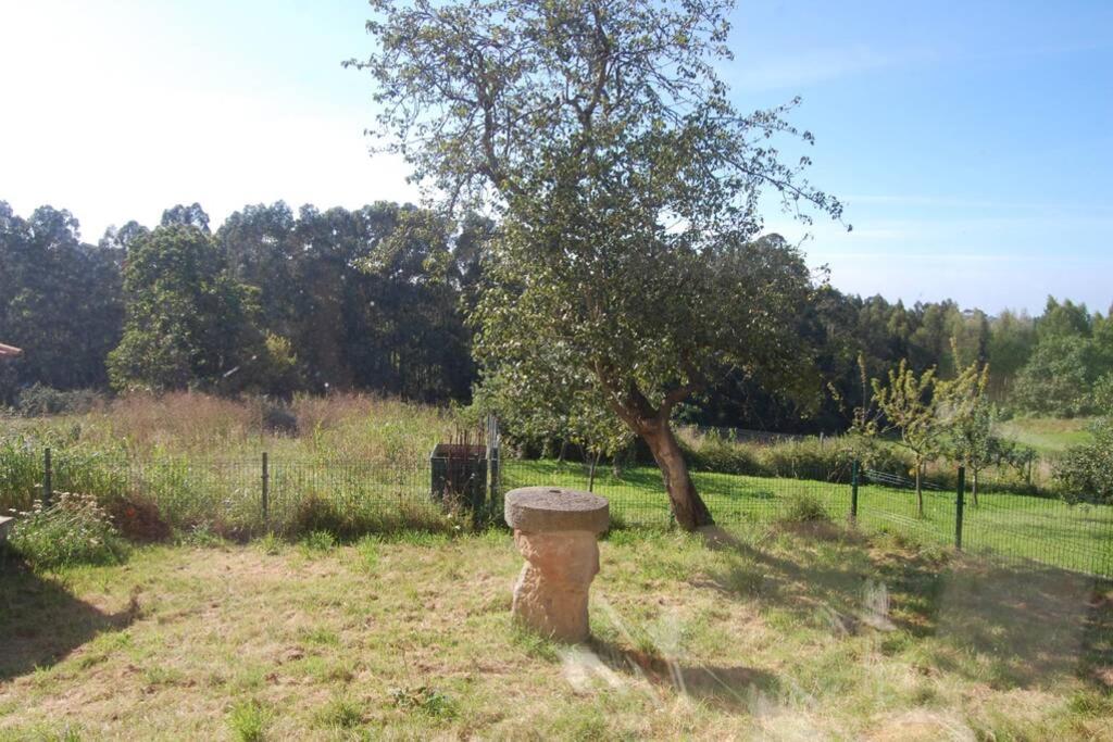 a stone pillar in a field with a tree at Casa Rural El Entamáu in Argüero