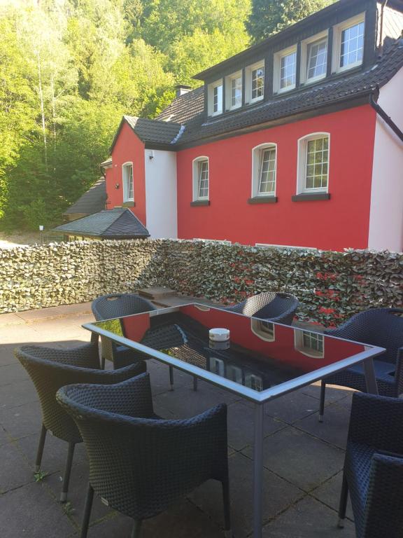 a table and chairs in front of a red house at Ferienwohnungen lemberg in Hagen