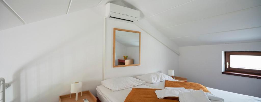 a white bedroom with a bed and a mirror at Apartments Hostin Roža Duga Uvala in Krnica