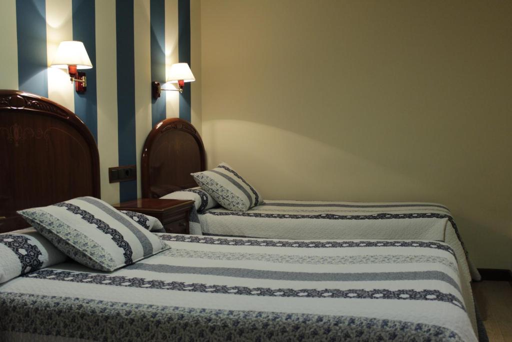 a group of three beds in a room at Hostal Ana Belen in Madrid