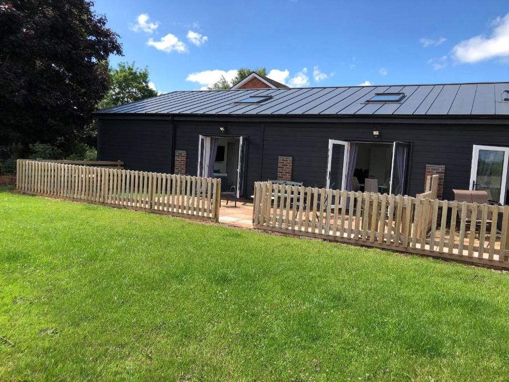 a black house with a wooden fence in front of a yard at 2 Barn Cottages in Whitchurch