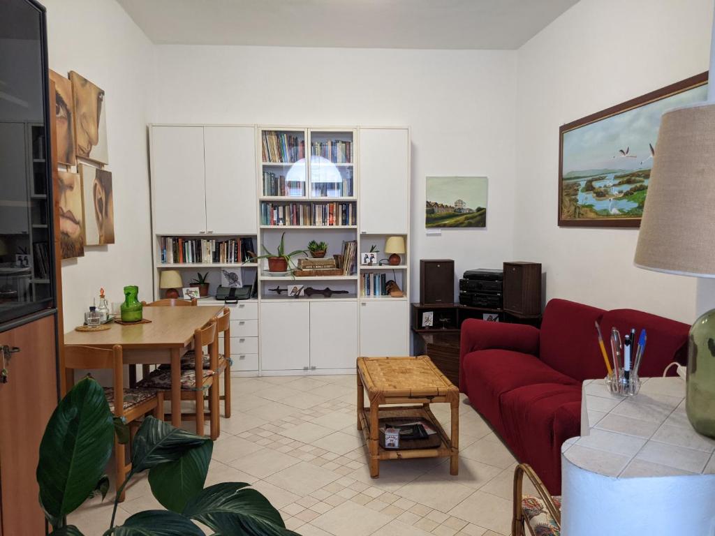 un soggiorno con divano rosso e tavolo di Il Nido - Casa Vacanze & Galleria d'Arte a Orbetello