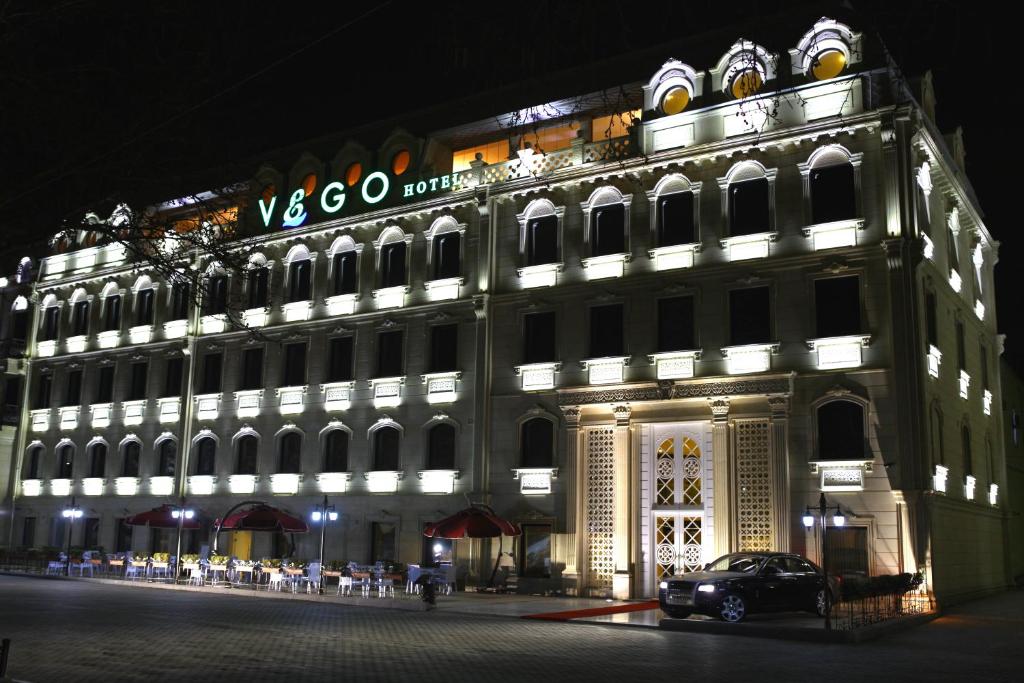 a large building with a car parked in front of it at Vego Hotel in Ganja