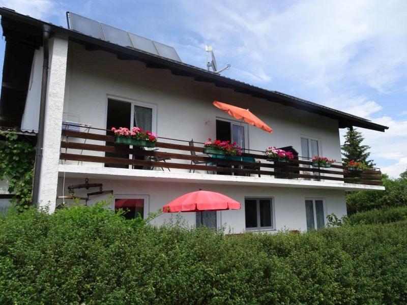 una casa blanca con dos sombrillas delante en Haus Strobl en Gstadt am Chiemsee