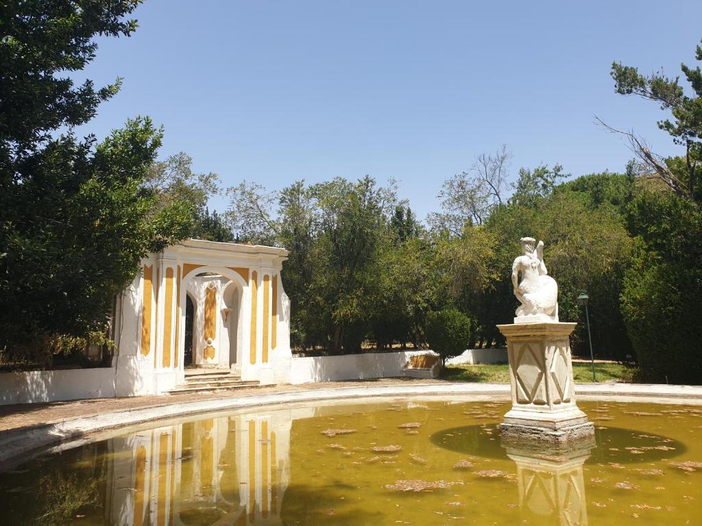 een fontein in een tuin met een standbeeld in het water bij Hotel Rural Quinta de Santo Antonio in Elvas