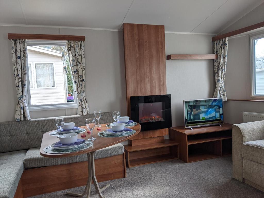 a living room with a coffee table and a tv at Caravan nearby Hastings Coghurst Hall Park in Guestling